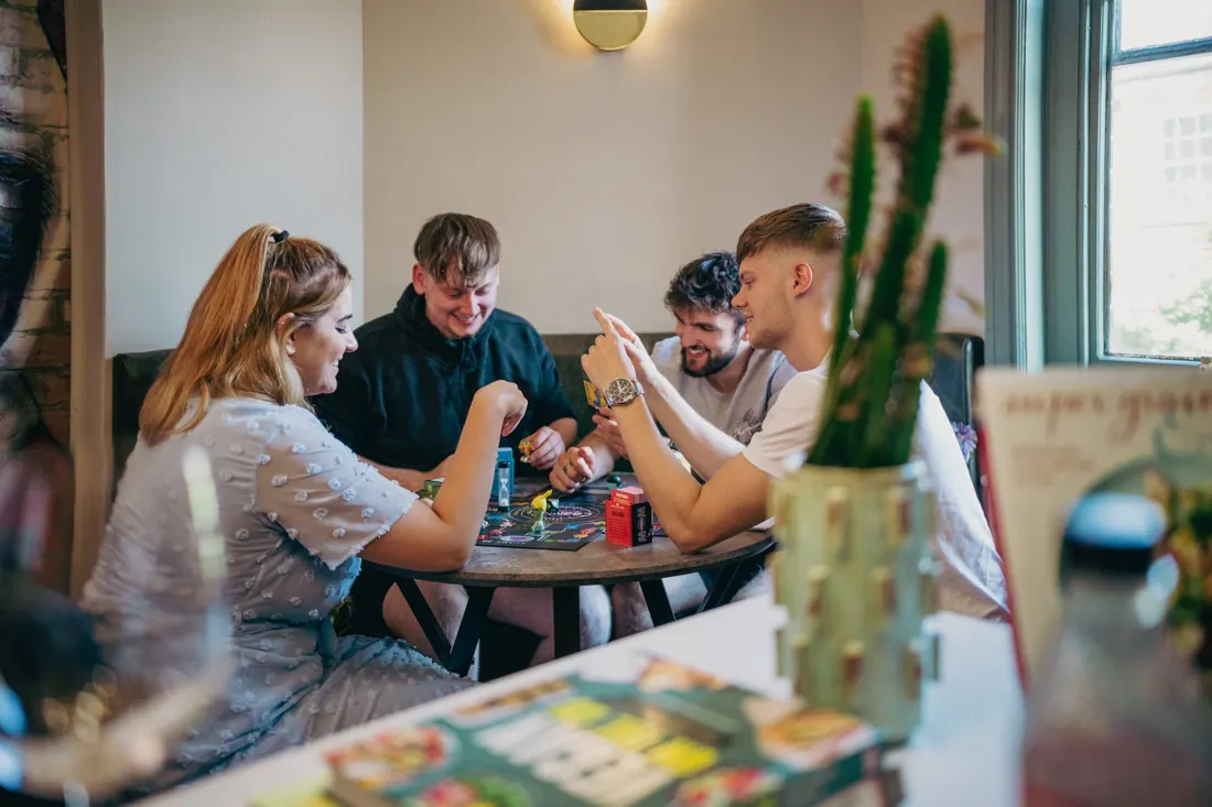 Friends playing a game at the Westie Warren dining table